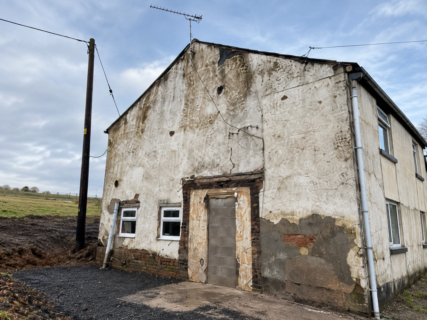 Farmhouse gable before work, with cracked and stained render