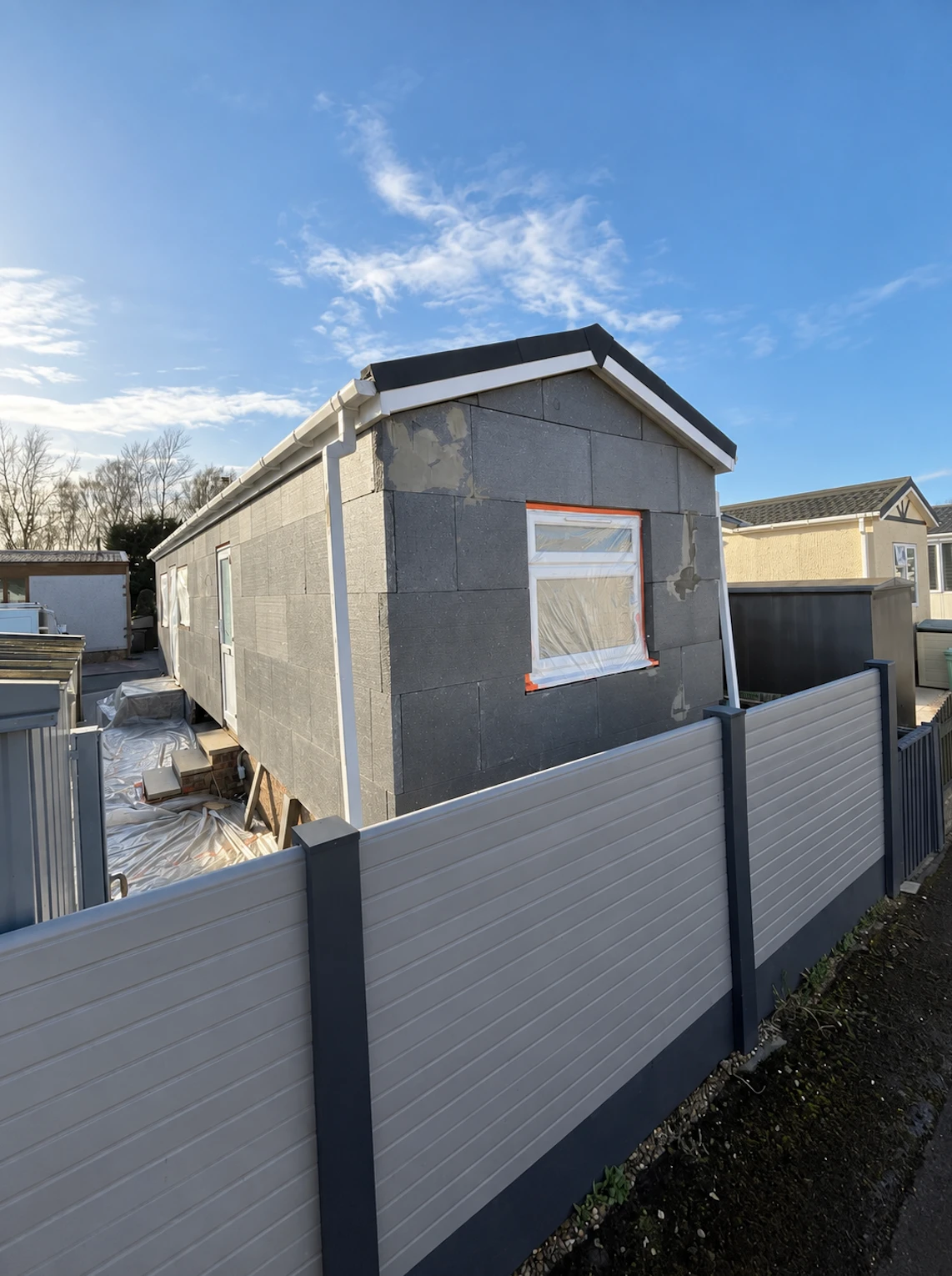 Park home wrapped in grey insulation boards with new white fascias and guttering